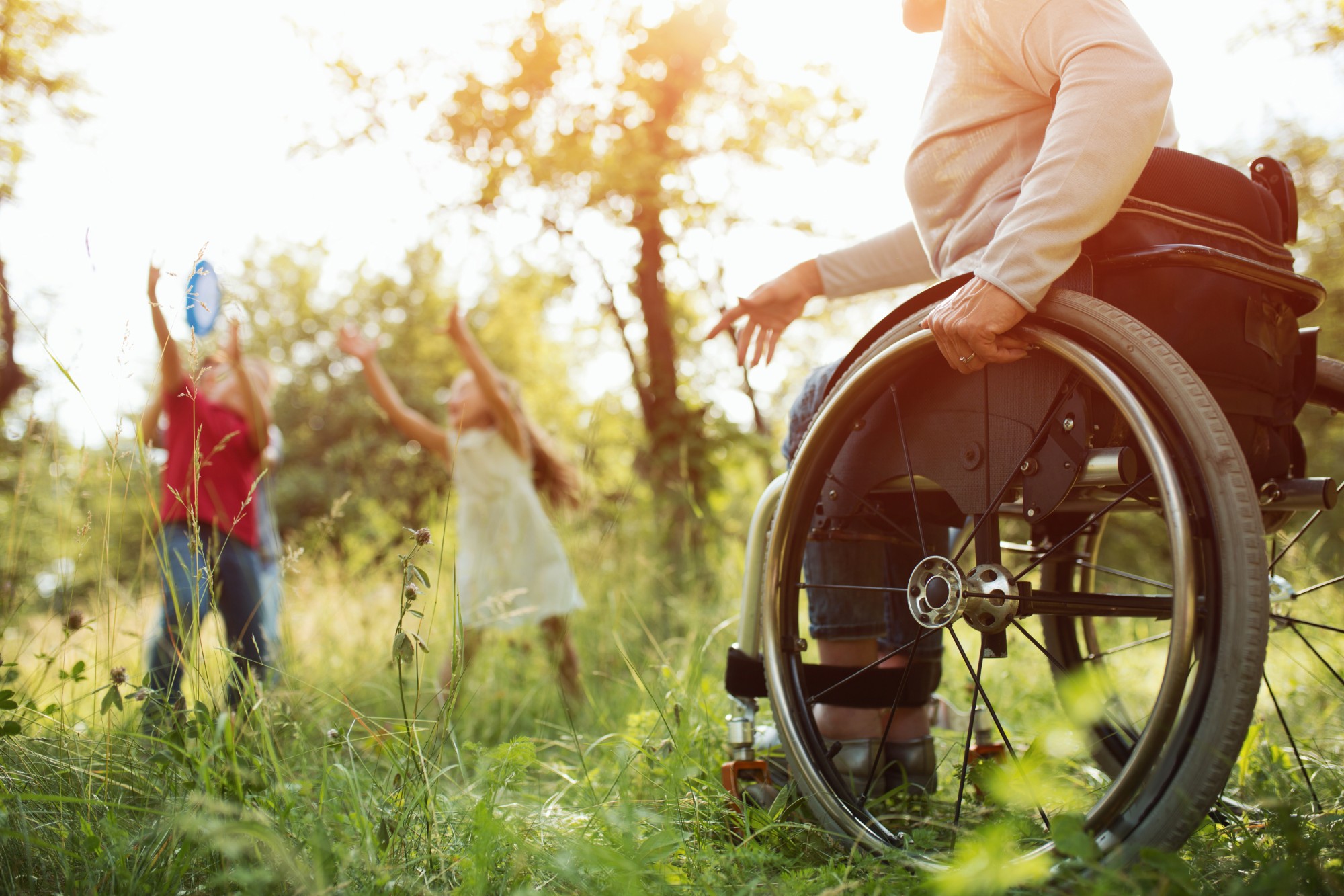 kobieta-z-paraplegia-ciasno-zwisa-pchania-wozka-inwalidzkiego-podczas-rzucania-frisbee-swoim-dzieciom-w-parku-szczegolowy-wyglad-wozka-inwalidzkiego_a.jpg