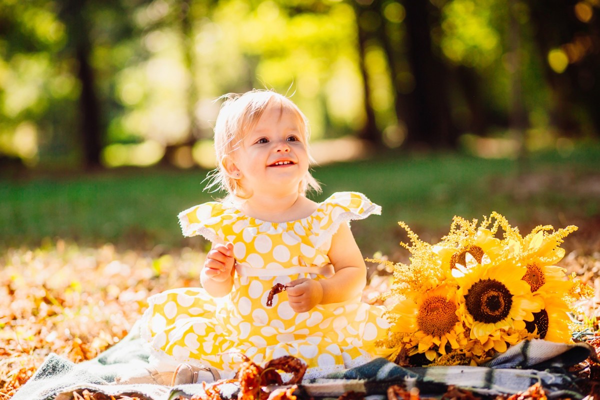 little-girl-yellow-spotted-dress-sits-blanket-park_a.jpg