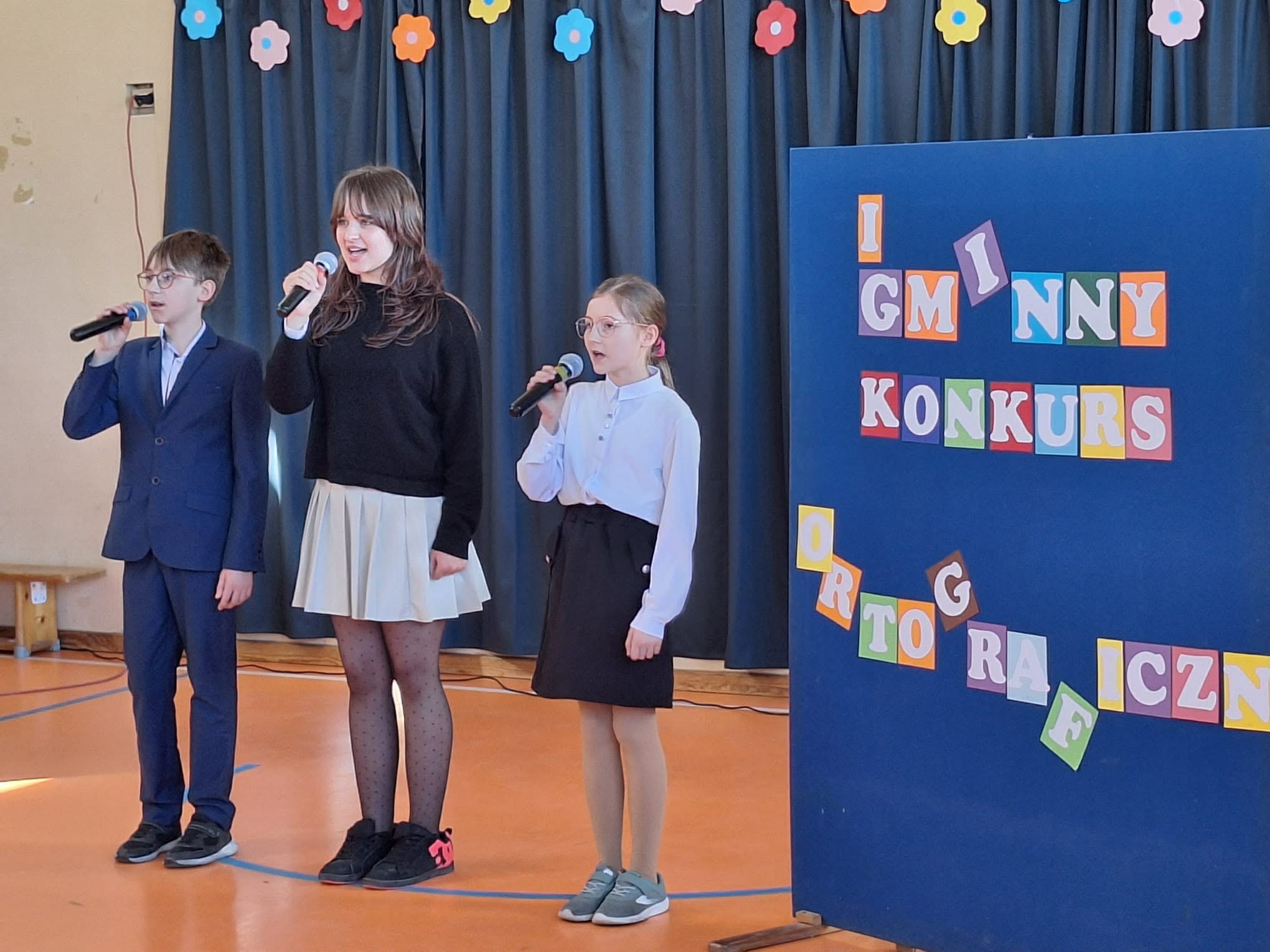 Trio z chóru SP1 śpiewająco rozpoczyna konkurs ortograficzny.jpg